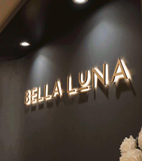 Illuminated signage of "Bella Luna" on a dark wall, with soft lighting creating an inviting atmosphere.